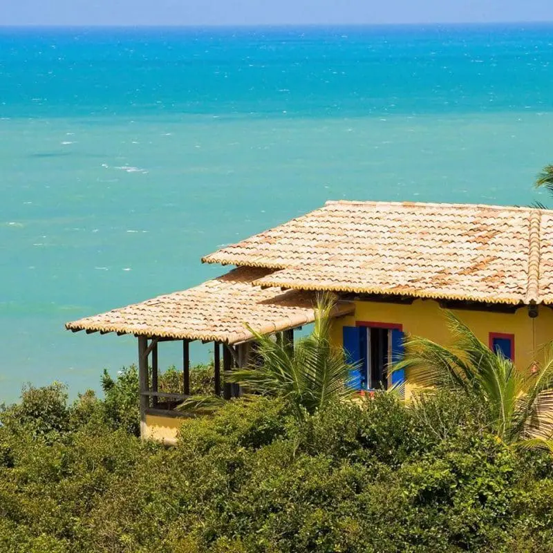 Vista das águas cristalinas da Praia das Minas, em Pipa, e um chalé com varanda. (Crédito: divulgação)