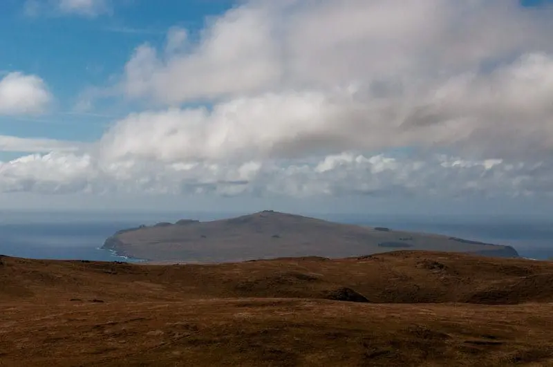 Montanhas, vales, nuvens e o azul marinho do Oceano Pacífico com sua linha reta dividindo o mundo em dois