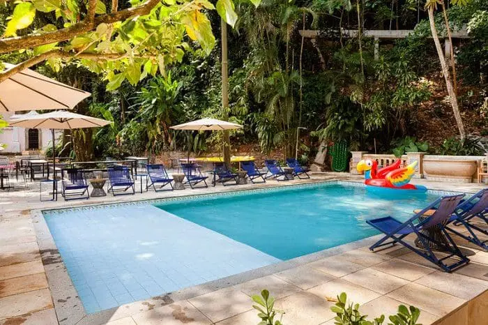 Área de lazer com piscina e cadeiras azuis no hotel JO&JOE Rio de Janeiro, no Largo do Boticário - RJ.