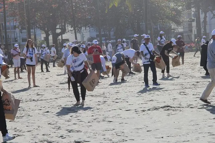 Integrantes da conferência coletam lixo em uma praia de Santos-SP em ato simbólico promovido pela 14ª Conferência Anual de Cidades Criativas.