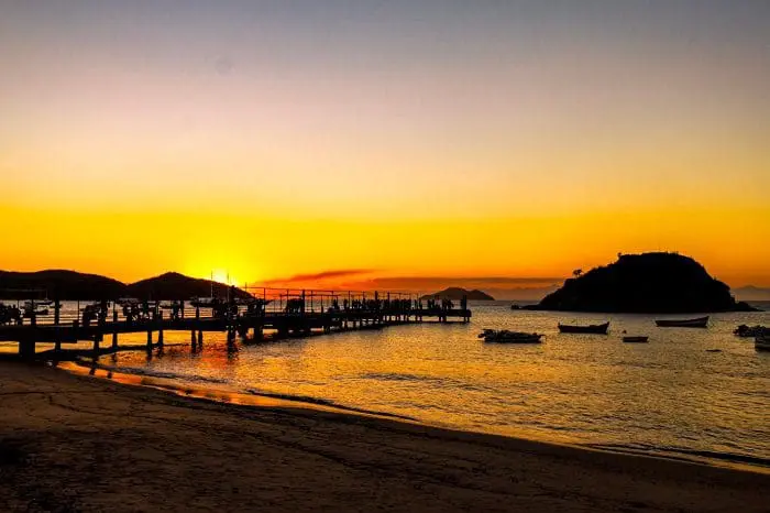 Foto de uma praia em Búzios no pôr do sol. Na temporada 2022/2023, a projeção é de que 300 mil cruzeiristas visitem a região.