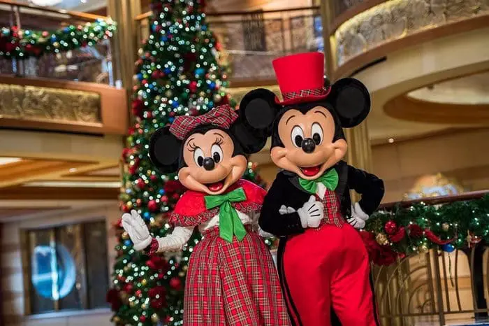Os personagens Minnie e Mickey, vestidos em trajes natalinos, na frente de uma árvore de Natal, para o Very Merrytime.