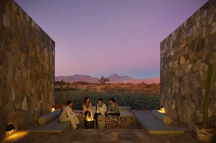 Imagem de pessoas tomando vinho em torno de uma fogueira no hotel Tierra Atacama, no Chile. O Chile flexibilizou as regras para entrada de turistas e a rede de hotéis comemora.