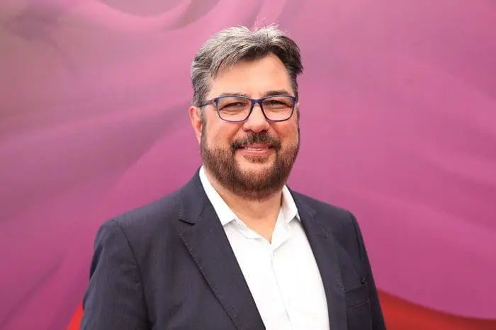 Roberto Haro Nedelciu, presidente da BRAZTOA, na frente de um fundo lilás.
