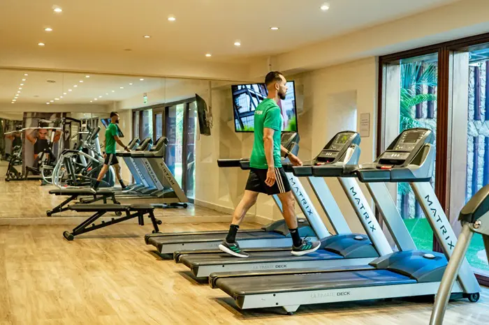 O The Westin Porto de Galinhas terá férias encantadas: foto da academia do resort, e de um rapaz andando em uma esteira