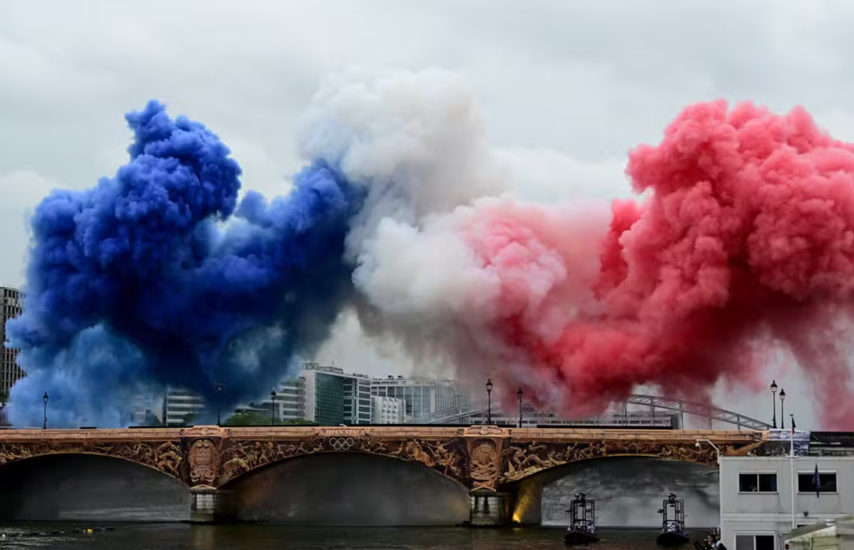 Nuvens de fumaça nas cores tricolores da bandeira da França são vistas na Pont d'Austerlitz durante a cerimônia de abertura — Foto Angelika Warmuth Reuters - Olimpíadas: prejudicam ou beneficiam turismo de Paris? Especialistas falam ao DIÁRIO
