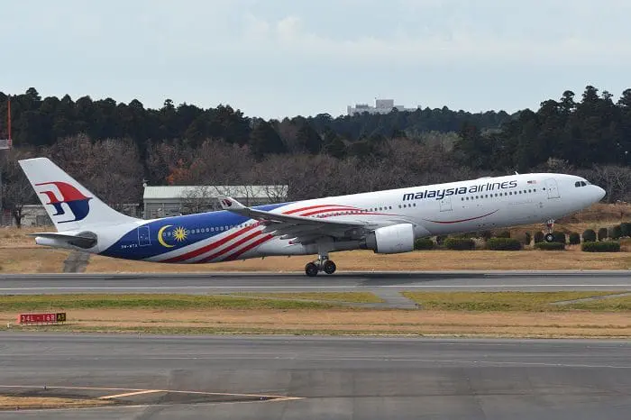 Foto lateral do avião da Malaysia Airlines decolando.