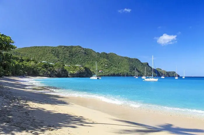 A Ilha Bequia, Kingstown, em São Vicente e Granadinas, com águas azuis turquesa e alguns barcos próximos da praia.