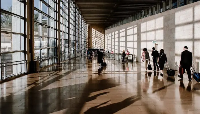Passageiros em corredor de terminal de aeroporto (foto: Briana Tozour - Unsplash)