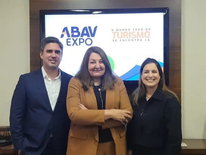 Antonio Neves Baptista, da Empetur; Magda Nassar, presidente da ABAV Nacional; e Milu Megale, da SETUR-PE, em frente à apresentação da ABAV Expo 2022, na televisão.