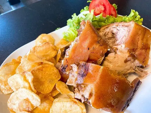Imagem do prato completo do Leitão á Bairrada, com batata chips e salada mista.