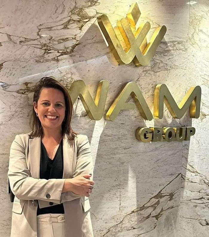 WAM Group anuncia Fernanda Oliveira: imagem da executiva em frente ao logo da empresa em dourado
