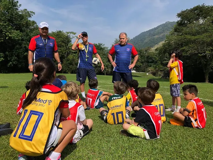 Zico 10 Camp: imagem de uma das edições anteriores da escola de futebol do craque Zico, no qual ele conversa com os jogadores mirins, que estão sentados na grama e vestem uniforme