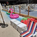 Boias de flamingo, melancia e morango no espaço "mar" do Bangalô de Praia da Booking.com
