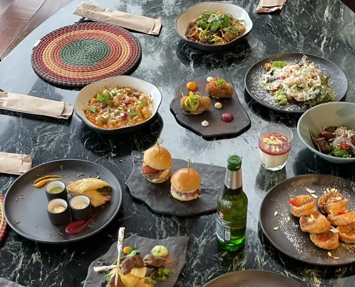 Visão superior de uma mesa com a Ceia Especial do Mercure Rio Boutique Copacabana. Há petiscos, hambúrueres e outras entradas. Além disso, o hotel terá Réveillon com menu especial e DJ.