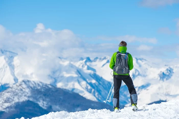 destinos_de_neve_sao_foco_da_primeira_super_semana_da_bwt Homem de costas, no topo de uma montanha de neve, com roupas de frio, segurando um ski. BWT oferece até 50% de desconto para destinos de neve na 1ª Super Semana de 2023