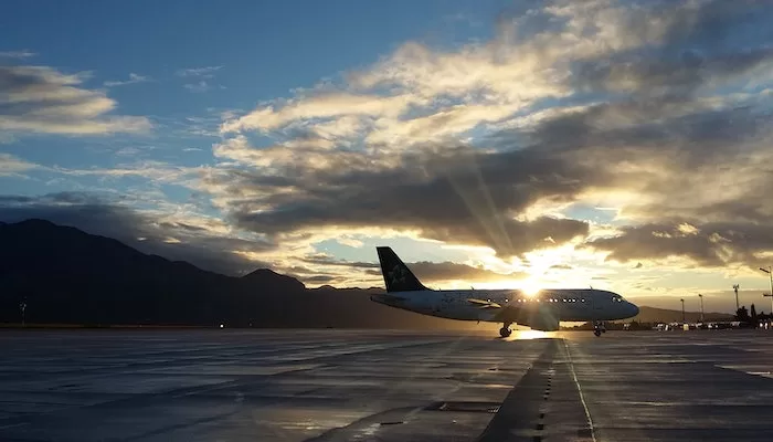 Foto de um avião estacionado no aeroporto. É fim de tarde e é possível ver o pôr do sol atrás da aeronave. A ANAC revela que em 2022, mais de 82,2 milhões de passageiros.