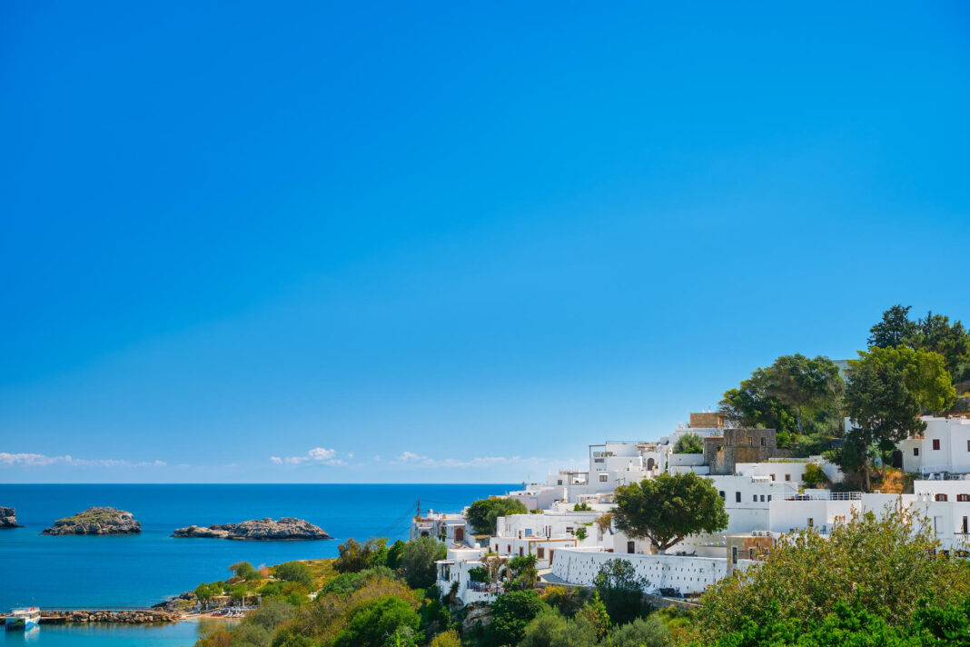 Vista da histórica vila de Lindos, na ilha grega de Rodes, um dos destinos que impulsionam o crescimento da intenção de viagens ao sul da Europa no verão de 2026. Ao fundo, o Mar Egeu completa um dos cenários mais emblemáticos do Mediterrâneo. Crédito: Magnific / Freepik Vista da histórica vila de Lindos, na ilha grega de Rodes, um dos destinos que impulsionam o crescimento da intenção de viagens ao sul da Europa no verão de 2026. Ao fundo, o Mar Egeu completa um dos cenários mais emblemáticos do Mediterrâneo. Crédito: Magnific / Freepik